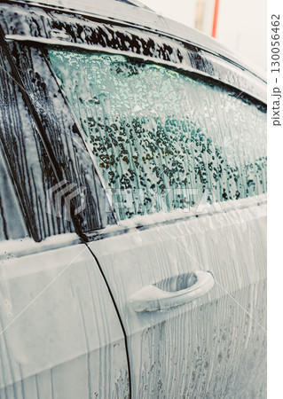 This visual illustrates the Car Wash Process, showcasing a soapy vehicle with glistening water droplets, emphasizing the detailed work needed for a perfect shine and sparkle for any car 130056462