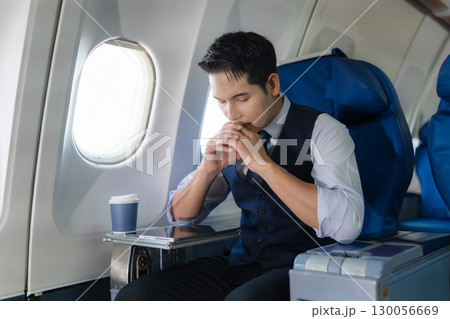 Tired and anxious Asian man sitting on a plane Passengers near the window. 130056669