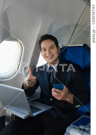 Traveling and technology. young business man working on Laptop and smartphone while sitting in airplane. 130056743
