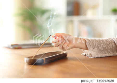 Woman hand lighting incense stick with a lighter at home Woman hand lighting incense stick with a lighter at home 130058086