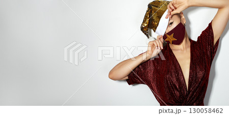Woman with red christmas hat, black medical mask. Fashion shiny style for xmas time. Protection from flu on holidays 130058462