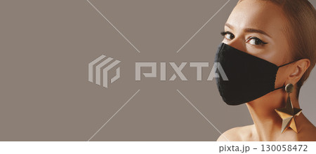 Beautiful Woman with Black Face Mask. Fashion Eye Make-up and Gold Accessories. Protection hygiene in virus pandemic Beautiful Woman with Black Face Mask. Fashion Eye Make-up and Gold Accessories. Protection hygiene in virus pandemic 130058472