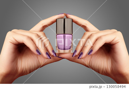 Manicured nails with lilac nail polish. Manicure with bright nailpolish. Fashion manicure. Shiny gel lacquer in bottle 130058494