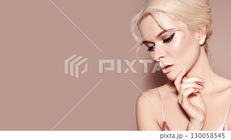 Sexy model with retro make-up, clean skin, blond hair on beige background. Elegant woman with fashion makeup, hairstyle 130058545