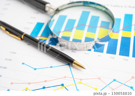 Magnifying glass on data business graphs paper. Magnifying glass on data business graphs paper. 130058810