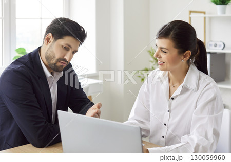 Confident business people looking at laptop monitor screen discussing company finance in office. Confident business people looking at laptop monitor screen discussing company finance in office. 130059960