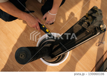 Top view of repairman using a steam cleaner to clean air conditioner parts placed in bucket, ensuring proper hygiene and maintenance. Concept of maintenance modern home appliance. 130060106