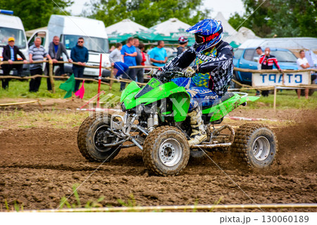 uzhhorod, ukraine - may 21, 2017: ATV rider accelerating on the dirt track. sport competition of green quad wheel vehicle in the mud uzhhorod, ukraine - may 21, 2017: ATV rider accelerating on the dirt track. sport competition of green quad wheel vehicle in the mud 130060189