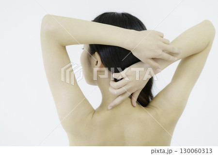 白背景のうなじと髪に手を添える若い女性の背中 130060313