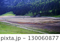 Dried lake bed surrounded by lush green mountains under a cloudy sky in early spring 130060877