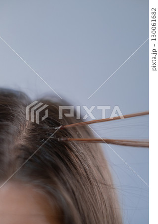 Hair extension specialist showing how to attach capsule to natural strand in professional beauty salon Hair extension specialist showing how to attach capsule to natural strand in professional beauty salon 130061682