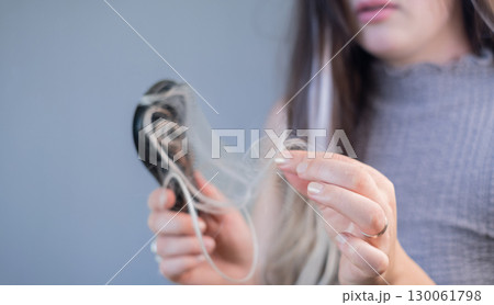 Young woman with hair loss holding hairbrush with strands showing weak brittle hair and hair breakage problem 130061798