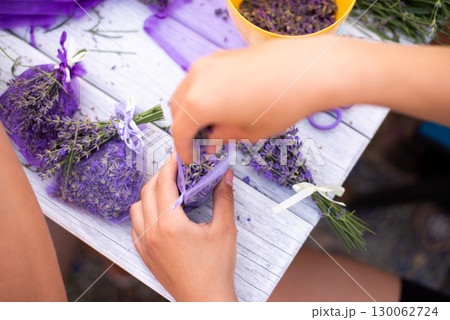 Process of making aromatic sachet and bouquets out of lavender flowers, view from above. White wooden table with lots of small aromatic pouches 130062724