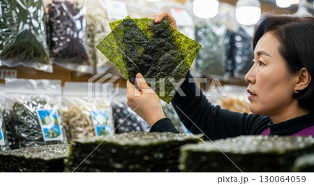 Asian woman examining seaweed sheets at grocery store Asian woman examining seaweed sheets at grocery store 130064059