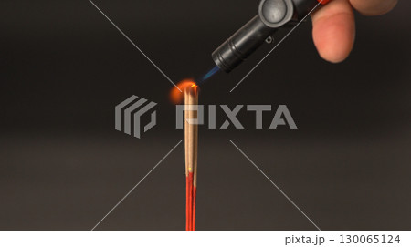 Lighting incense stick with small torch flame close up hand holding torch red incense dark background spiritual calm ritual meditation relaxation focus 130065124