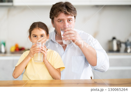 Father and daughter drink water from glasses Father and daughter drink water from glasses 130065264
