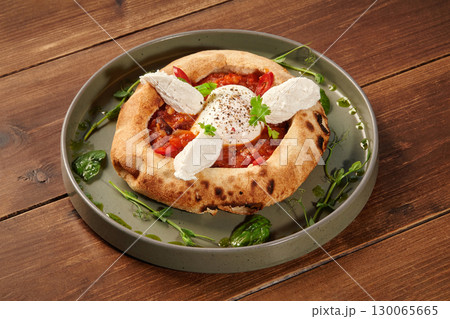 Delicious italian style pizza with egg, tomato sauce, and cheese on wooden table 130065665