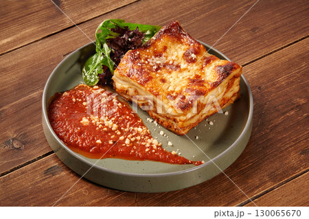 Delicious lasagna bolognese with tomato sauce and parmesan on wooden table Delicious lasagna bolognese with tomato sauce and parmesan on wooden table 130065670
