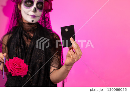 Woman With Sugar Skull Makeup Holding Black Credit Card on Dia De Muertos Woman With Sugar Skull Makeup Holding Black Credit Card on Dia De Muertos 130066026