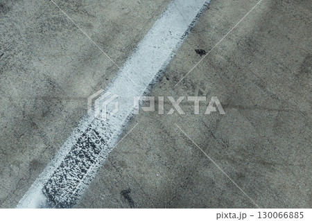 Weathered concrete pavement displaying worn white traffic markings and textured surface details 130066885
