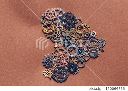 Intricate Clockwork Gears and Mechanical Components Arranged on Textured Paper Copper Surface 130066886