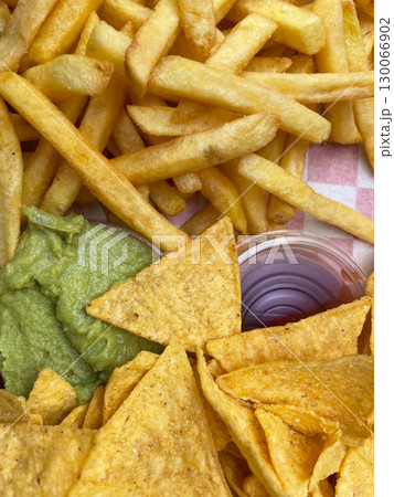 Golden crispy tortilla chips with creamy guacamole and french fries appetizer platter Golden crispy tortilla chips with creamy guacamole and french fries appetizer platter 130066902