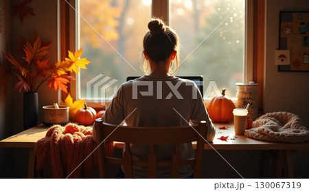 Person working in cozy autumn home office, back view 130067319