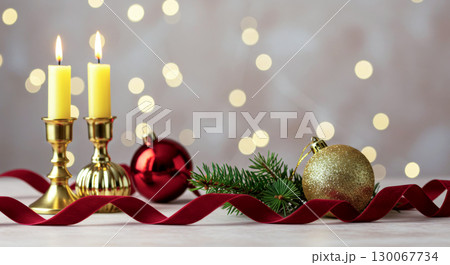 Holiday candles and ornaments on a table with a red ribbon and sparkling lights. Christmas atmosphere. 130067734