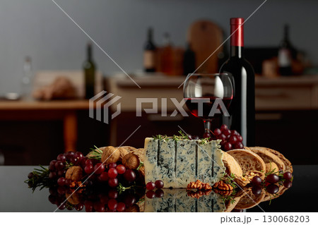 Gorgonzola cheese with ciabatta, walnuts, grapes, and red wine on a kitchen table. 130068203
