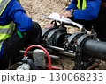 Engineers are looking at blueprints and using tools to connect pipes. 130068233