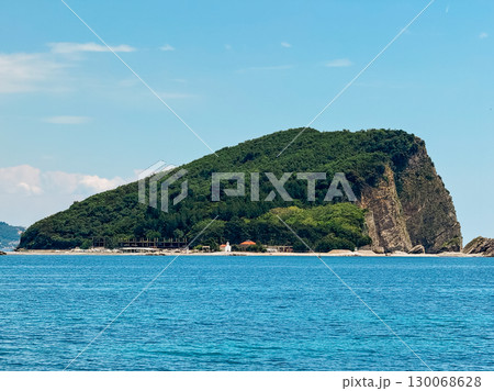 Island in Montenegro covered with forest surrounded by blue sea. Landscape, coastal environment, and natural wilderness in seascape. 130068628