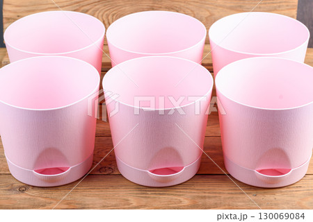 Empty pink plastic flower pots with trays on wooden background. Empty pink plastic flower pots with trays on wooden background. 130069084