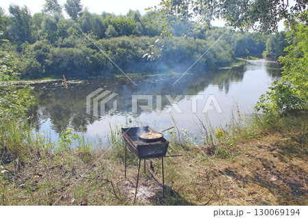 Cooking fried mussels in frying pan. Frying fresh mussels and onions near river 130069194