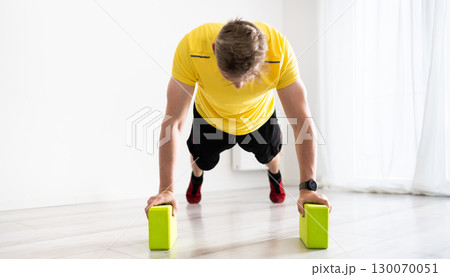 Young Man Doing Routine Sport At Home With Yoga Blocks Young Man Doing Routine Sport At Home With Yoga Blocks 130070051