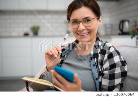 Girl In Glasses Uses A Calculator And Writes Down Expenses And Income In A Notebook Girl In Glasses Uses A Calculator And Writes Down Expenses And Income In A Notebook 130070064