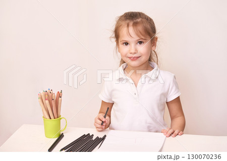 Young caucasian female child drawing with colored pencils in bright room wearing Young caucasian female child drawing with colored pencils in bright room wearing 130070236
