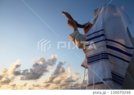 Jewish man blowing the Shofar horn of Rosh Hashanah - New Year. Shofar at Sunrise 130070298