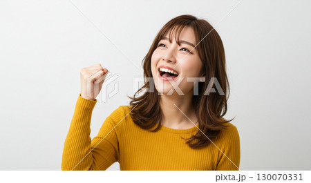 右手でガッツポーズをして斜め上を向いた若い日本の女性-夢や目標に向かって気合を入れる様子 130070331