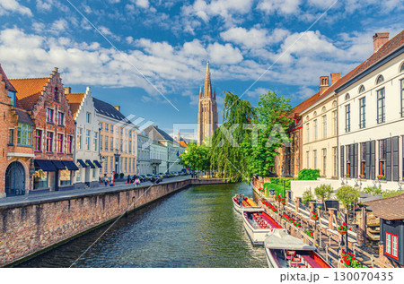 Church of Our Lady, Dijver water canal with promenade embankment, tourists boat near wharf and medieval houses in Brugge old town quarter, Bruges city historic centre, West Flanders province, Belgium 130070435