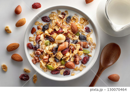 Stylish tableware.  Top view of a tray of muesli in nuts on a bowl and milk jug on a white background. Classic breakfast. 130070464