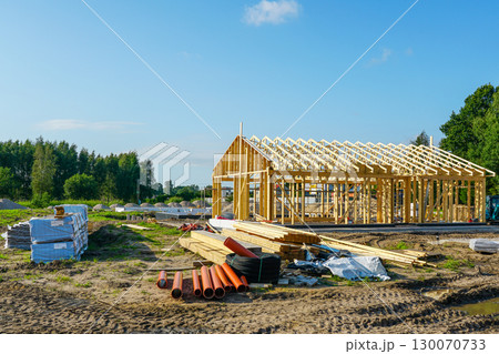 New modern wooden house construction with timber framing and building materials on site New modern wooden house construction with timber framing and building materials on site 130070733