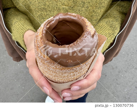 sweet trdelnik with nutella in the hands of a girl in summer. High quality photo 130070736