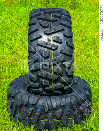Pair of rugged ATV tires with aggressive tread pattern stacked on grass for off-road performance 130070774