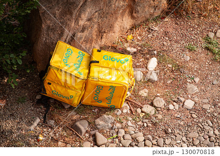 08/25/2025 Georgia, Tbilisi, Delivery packages, Glovo company, left on stony ground, near bushes, outdoors, no people 130070818