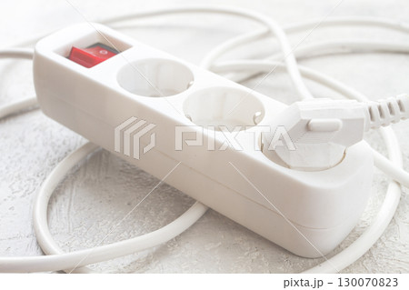 Power strip with multiple sockets and a switch in a cluttered setup on a textured surface during daytime Power strip with multiple sockets and a switch in a cluttered setup on a textured surface during daytime 130070823