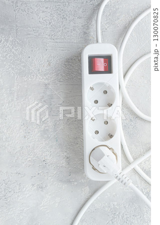 Power strip with multiple sockets and a switch in a cluttered setup on a textured surface during daytime Power strip with multiple sockets and a switch in a cluttered setup on a textured surface during daytime 130070825