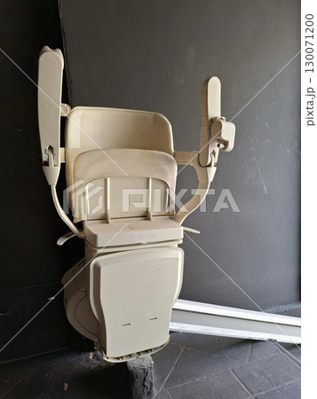 A wheelchair lift designed for easy access in a contemporary building, featuring sturdy arms and a spacious seat, ensuring mobility assistance for individuals with disabilities. 130071200