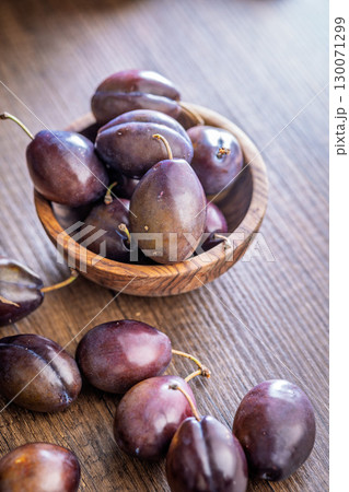Ripe plums on wooden table. 130071299