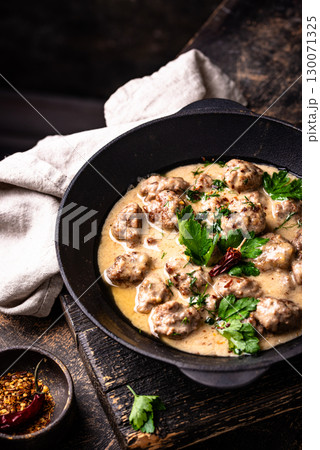 Meatballs in sour cream sauce in a frying pan 130071325