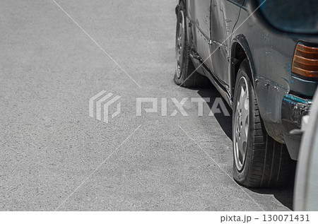 The twisted hull of the left side of the old car is dark green with dents, scratches, damage to skin elements, absence of decorative elements, the pressure in the wheels is deflated. Empty copy space The twisted hull of the left side of the old car is dark green with dents, scratches, damage to skin elements, absence of decorative elements, the pressure in the wheels is deflated. Empty copy space 130071431